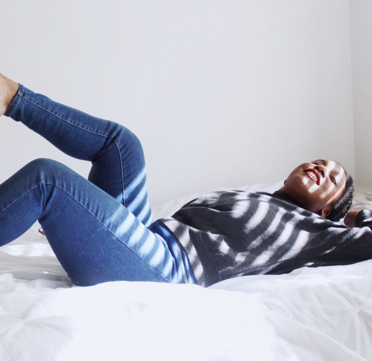 woman lying on bed in sun looking very content