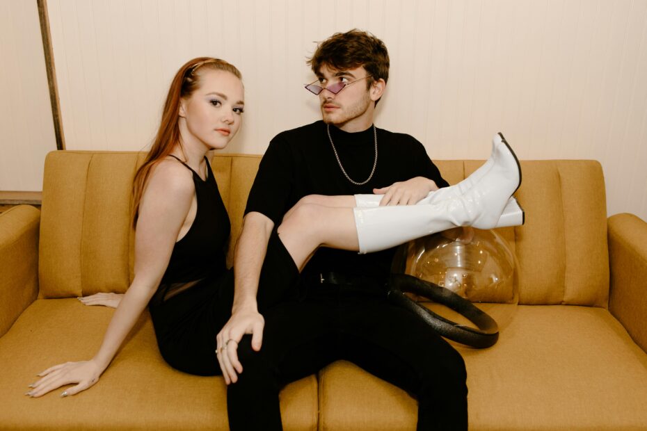 Couple seated on couch. Woman wearing white boots